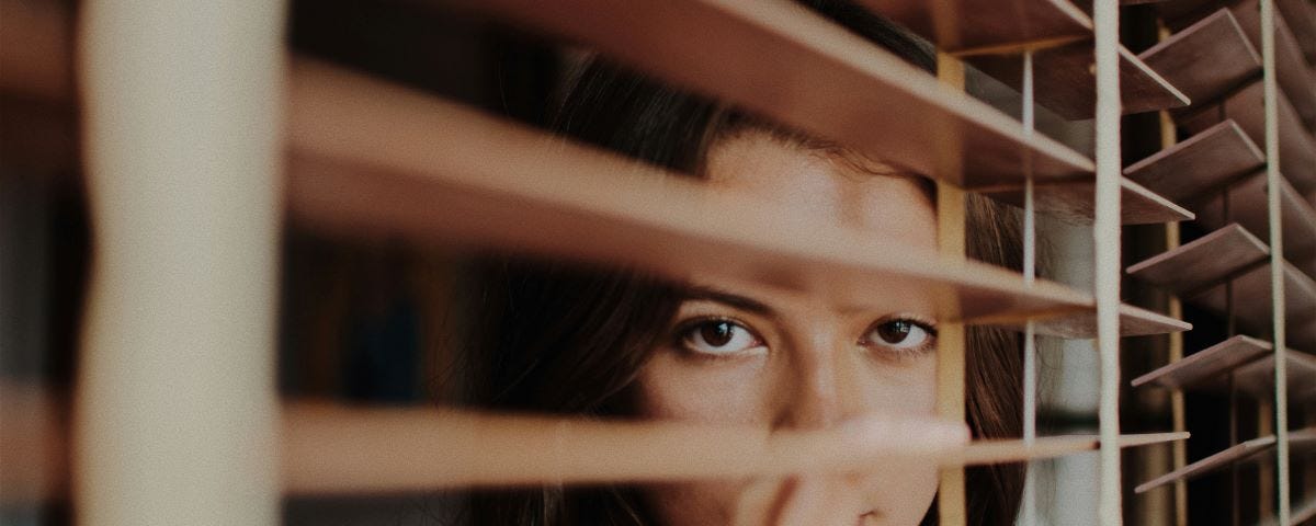 A woman peeping through blinds