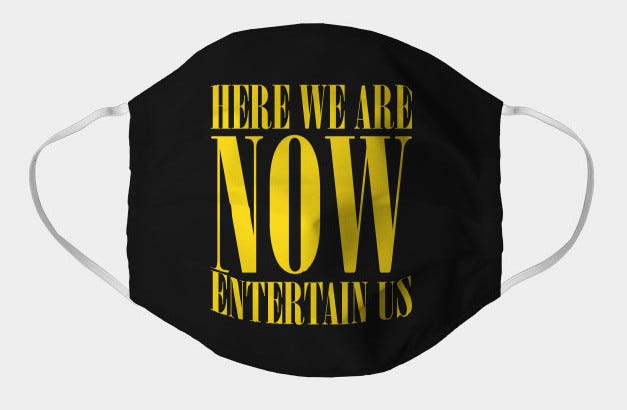 A black facemask with “Here we are now, Entertain Us” written in yellow across the front