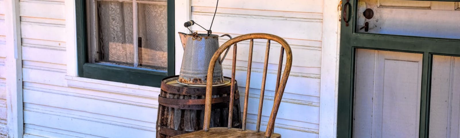 Old House, wood porch, with a wooden chair sitting empty and a barrel beside the chair, a peaceful image.
