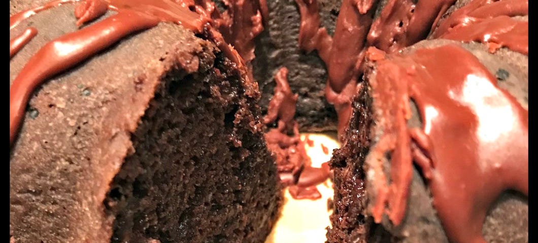 A glazed chocolate Bundt cake with a slice missing