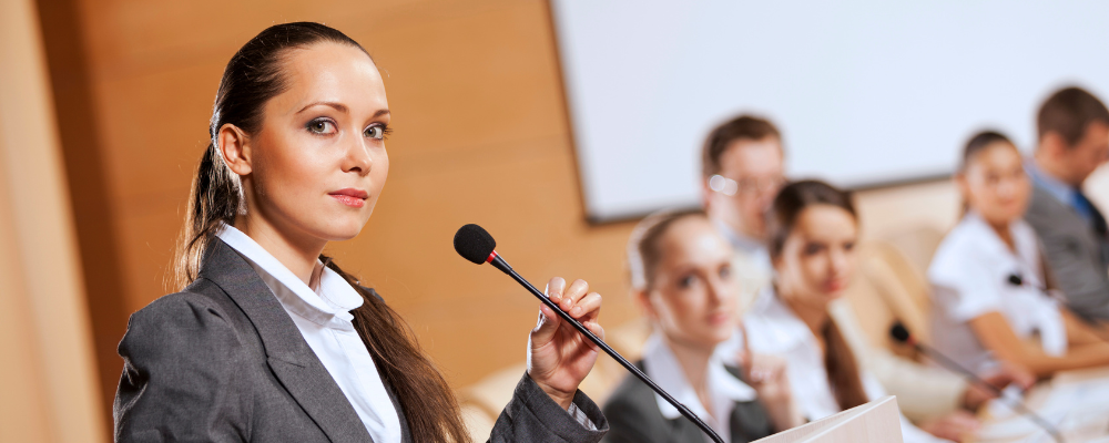 Young business woman at microphone about to speak to a group