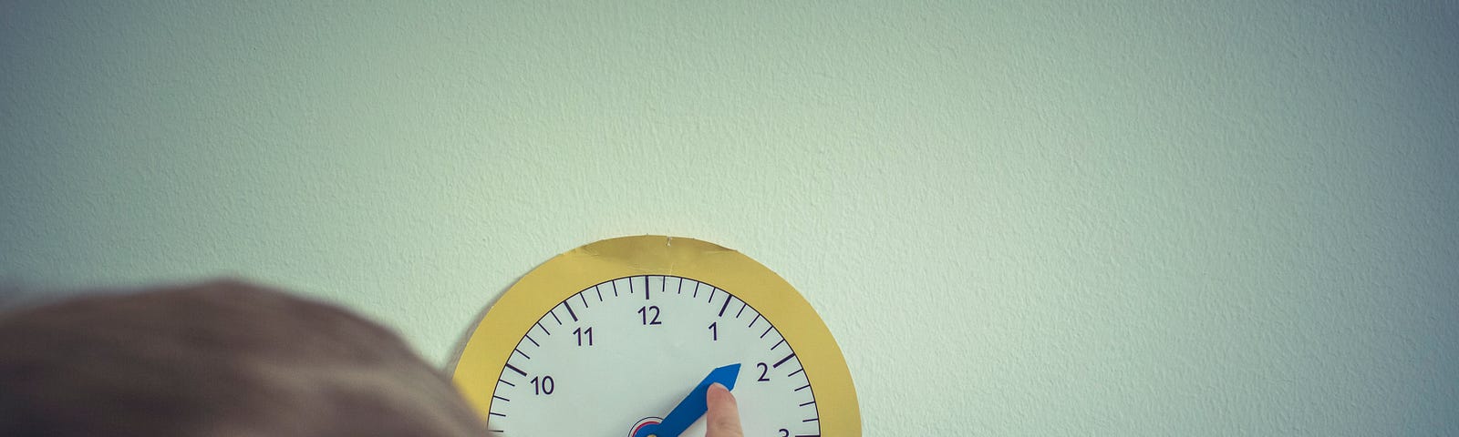 Child touching a clock on the wall