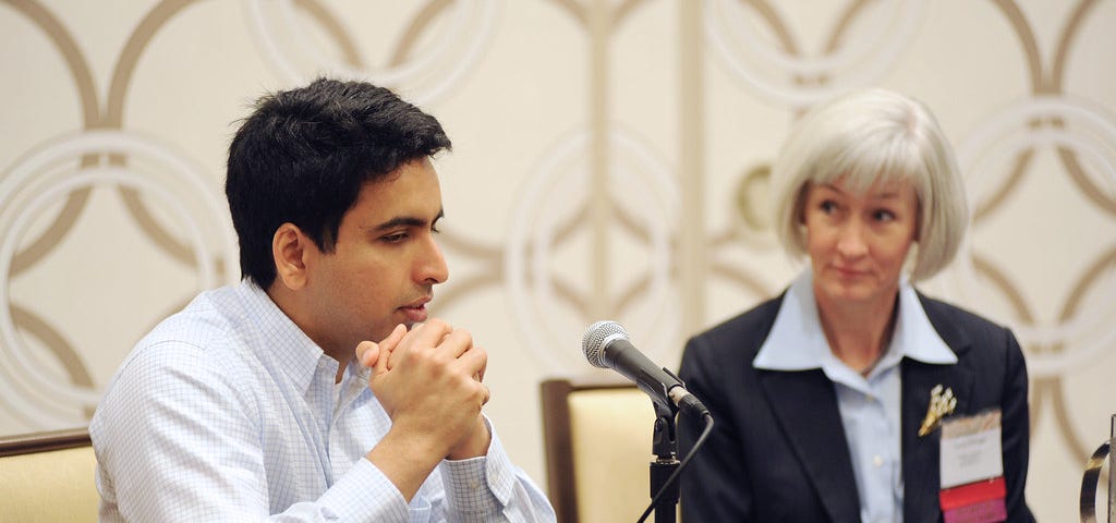 Sal Khan speaking into a chorded mic on his table