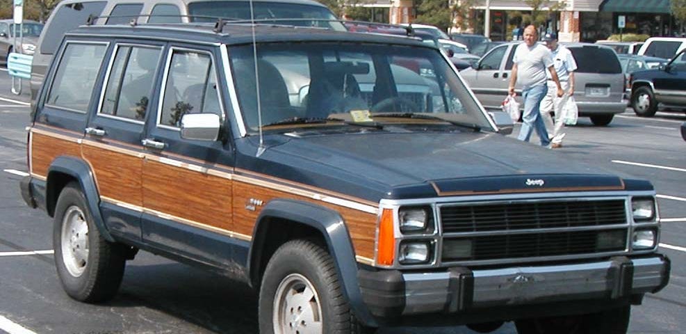 1987 Jeep Cherokee Wagoneer truck. Navy blue with wood panels on the side.