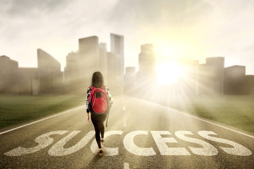 Young lady walking up a road that has success written in the middle of it.