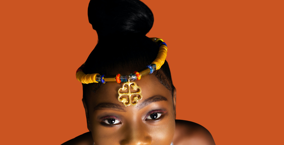 Young pretty woman in traditional orange African attire. Photo credit: canva.