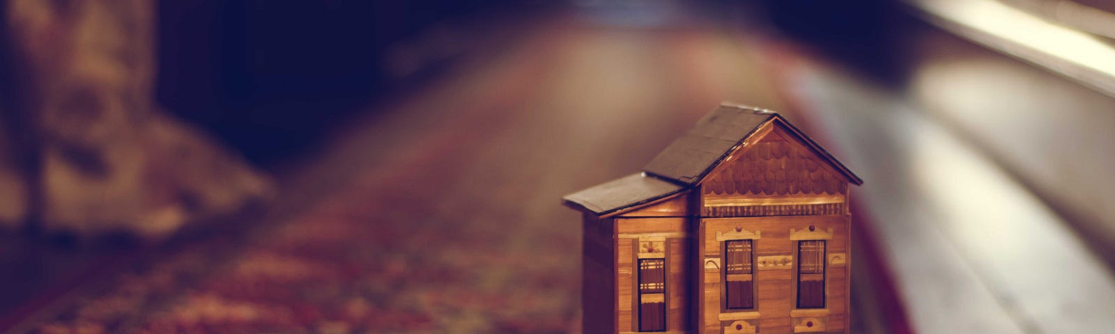 A close-up of a small wooden dollhouse on an oriental rug.