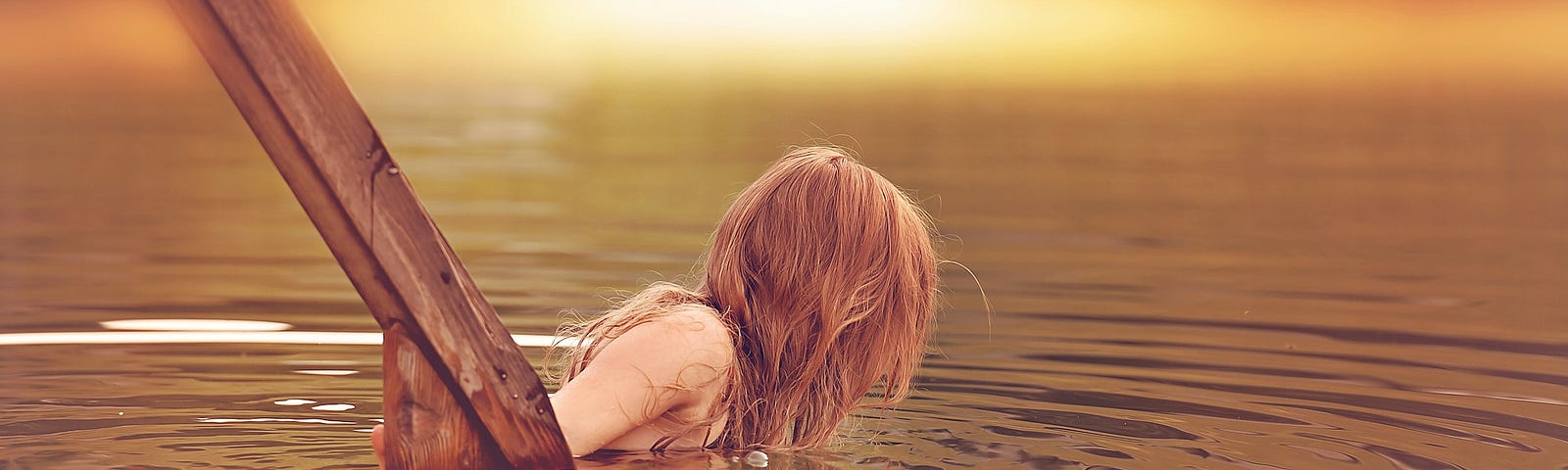 An attractive girl is moving down into some water. You can only see her from the side, and her hair is covering the upper torso — the only bit not submerged — but she looks to be at least topless.