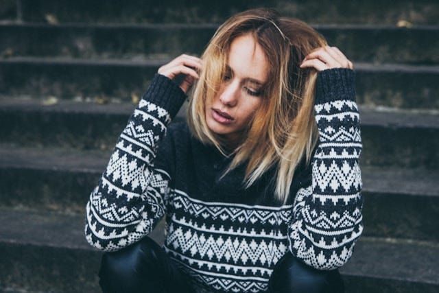 Young lady wearing black and white sweater looking tired and distraught