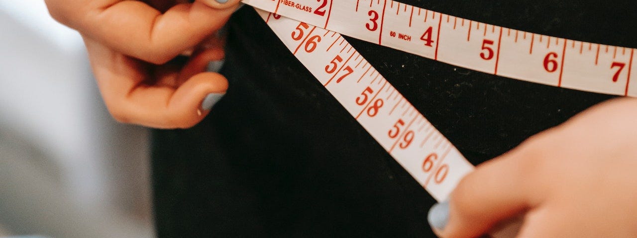 A woman measures her waistline.