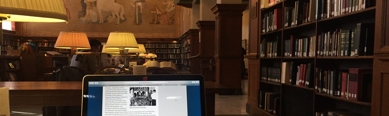 Laptop and notebook on a table in a library reading room