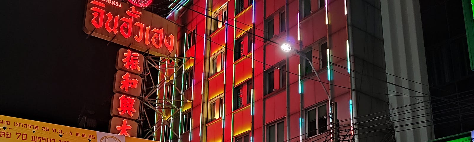 chinatown building with red neon lights and cars driving past in the foreground