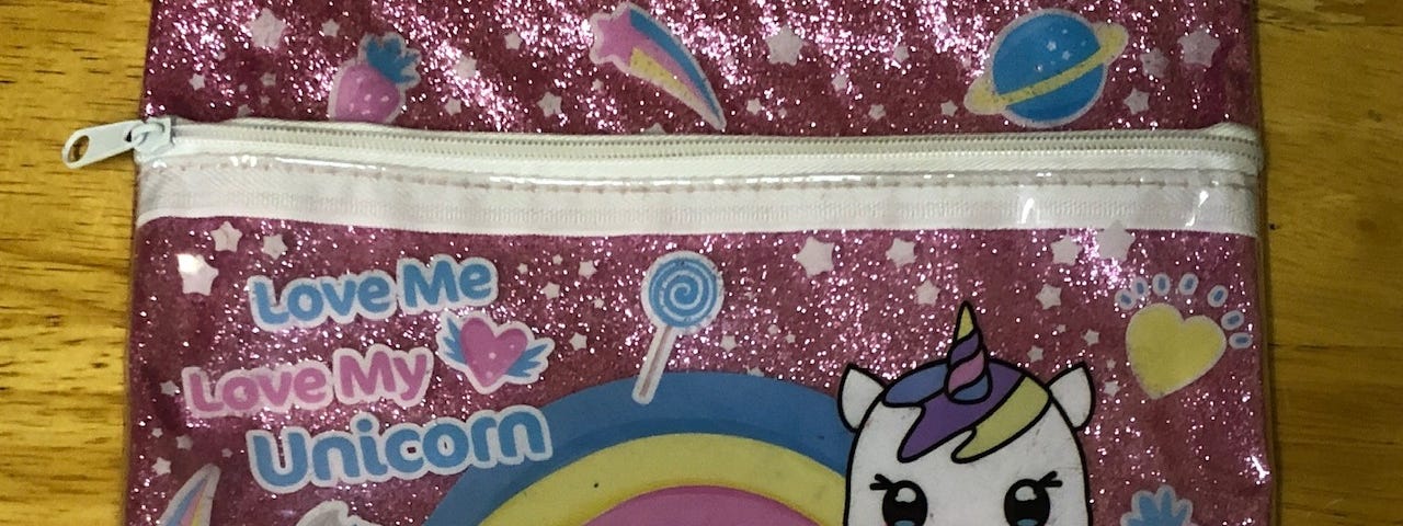 A pink pencil case with a white unicorn and the words “Love My Unicorn”