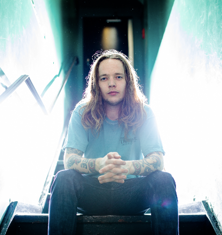 Billy Strings sits at the top of a staircase. Strings is a famous bluegrass musician.