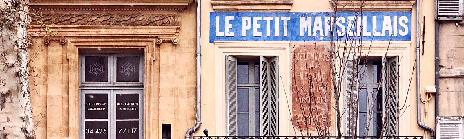 A tall Parisian apartment building with a cafe on the ground floor. Mother in Law in Paris