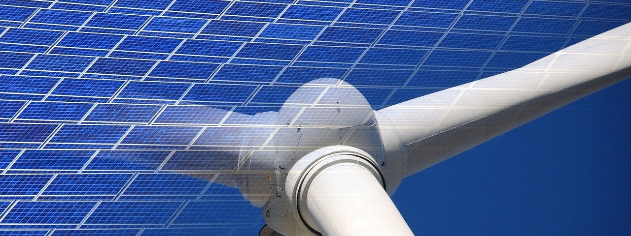 IMAGE: A long distance shot of a solar panel field, and a closeup of the vortex of a windmill