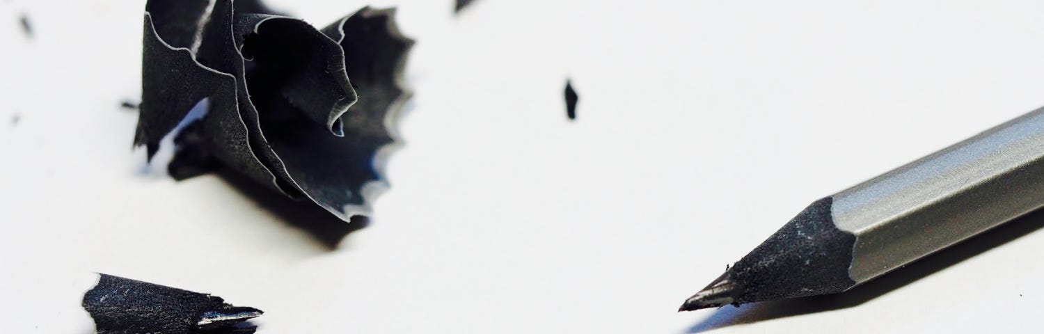 silver pencil with black tip and black sharpening shavings on a white background