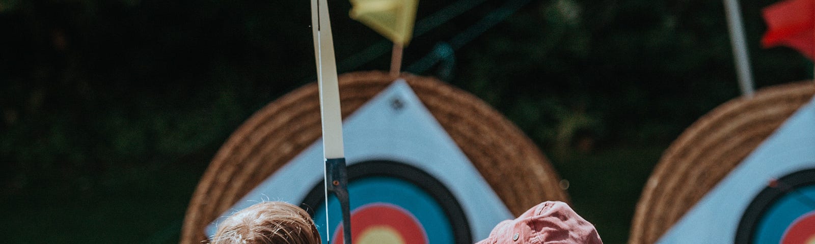 Mother shows a child to aim at the bow at the target before shooting — Photo by Annie Spratt on Unsplash