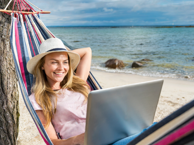 lazy beautiful woman in hammock enjoying life having laptop on lap at the beach