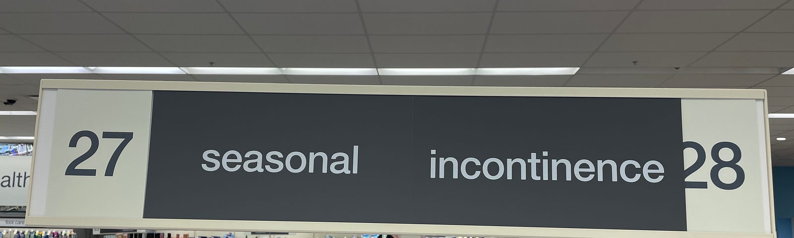 A sign demarcating aisles 27 and 28 in a Florida Walgreens reading, “27 Seasonal Incontinence 28”.