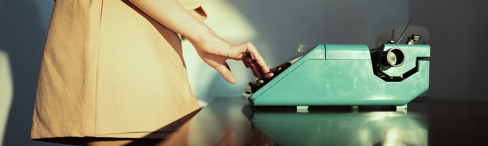 A woman stands next to a turquoise typewriter
