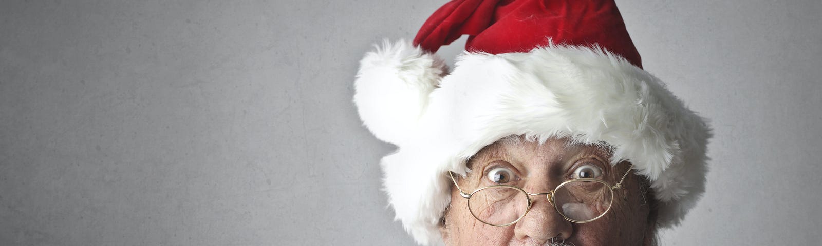 An image of a bearded Santa in red suit and hat and glasses with a shocked face