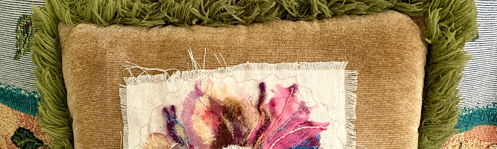 A floral fiber art piece used as a pillow embellishment