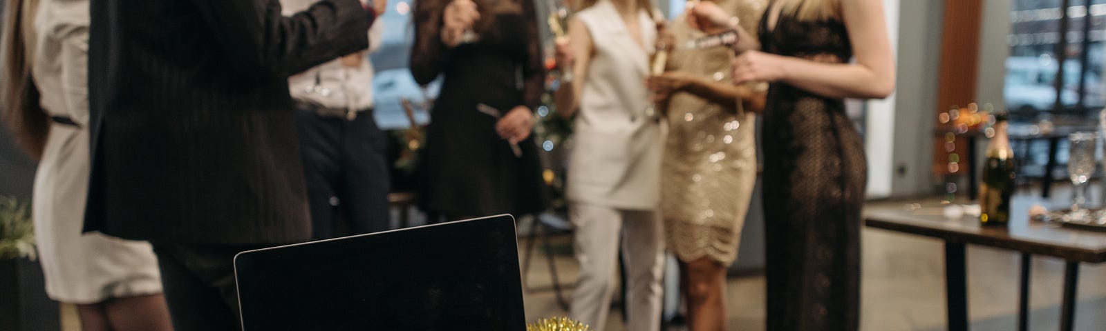 A laptop surrounded by tinsel with, in the background, staff members clutching drinks.