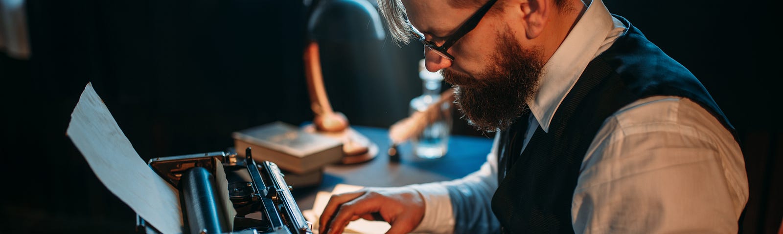 Bearded journalist in glasses typing on typewrite