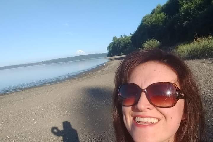 Social Equity Case Manager Sarah Davis in brown sunglasses taking a selfie at the beach