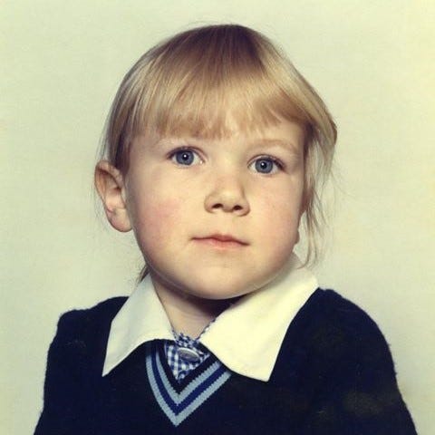 School photo of the author, aged 5, in a blue and white school uniform.