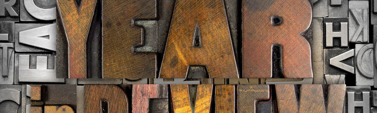 A graphic for an end of the year retrospective before New Year’s Day with the words “Year in Review” in wooden letters