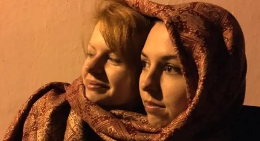 Photo of two women’s faces, wrapped in one scarf