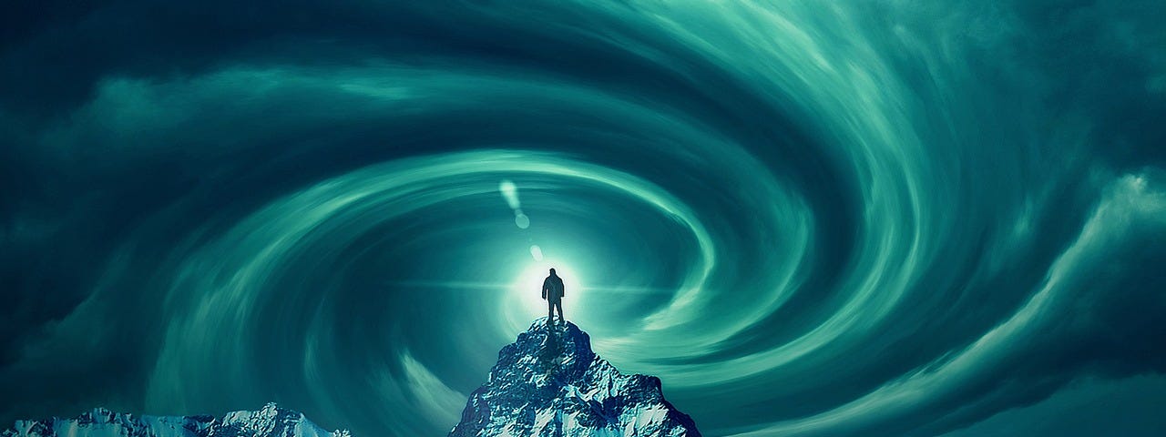 A man standing on the tip of a snowy, craggy mountain peak, surrounded by a swirl of cloud energy in the sky above him.