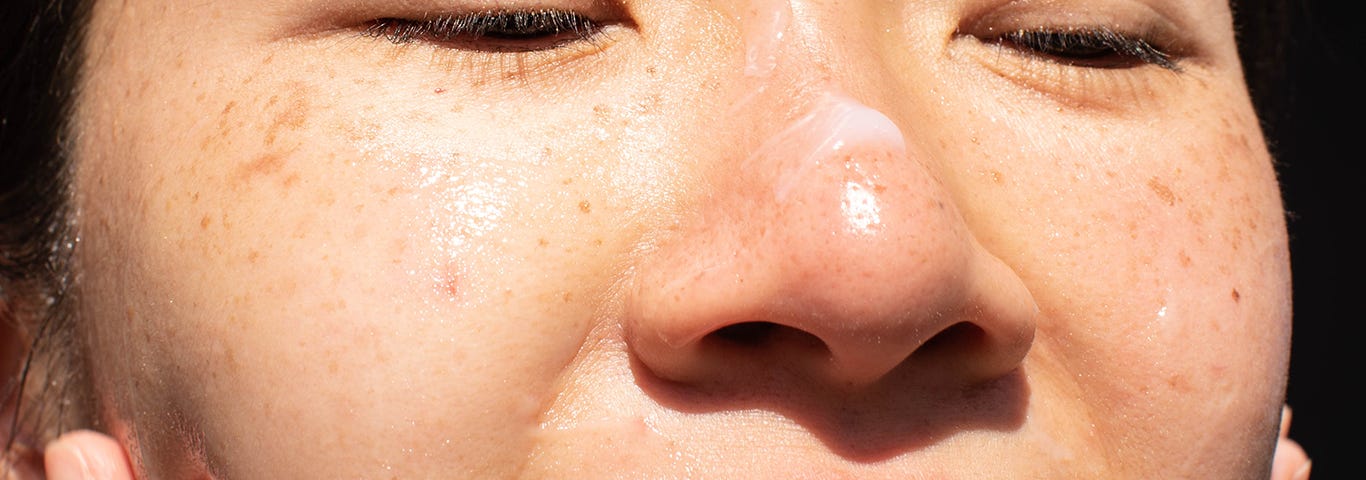 Person applying face moisturizer to their skin