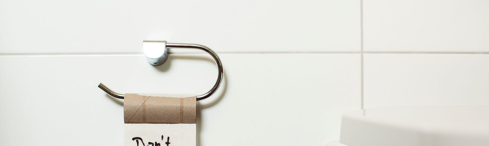 A photo of a restroom and a toilet paper roll that says “don't panic”.