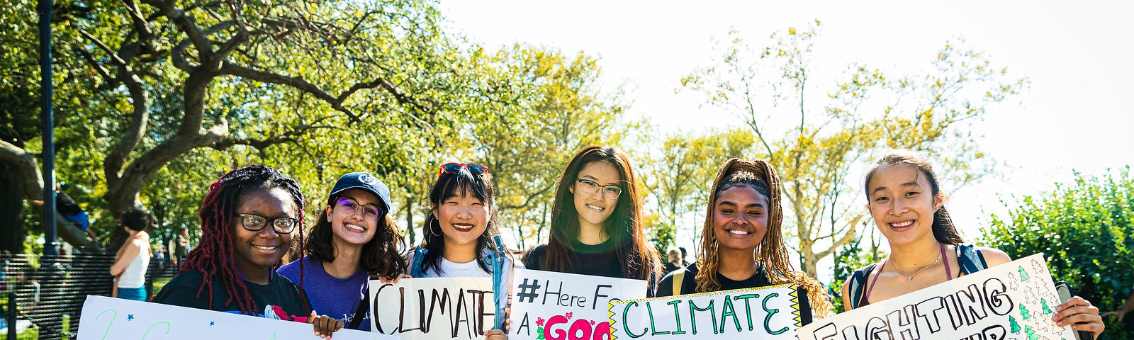 A diverse group of young women hold up signs about climate justice.