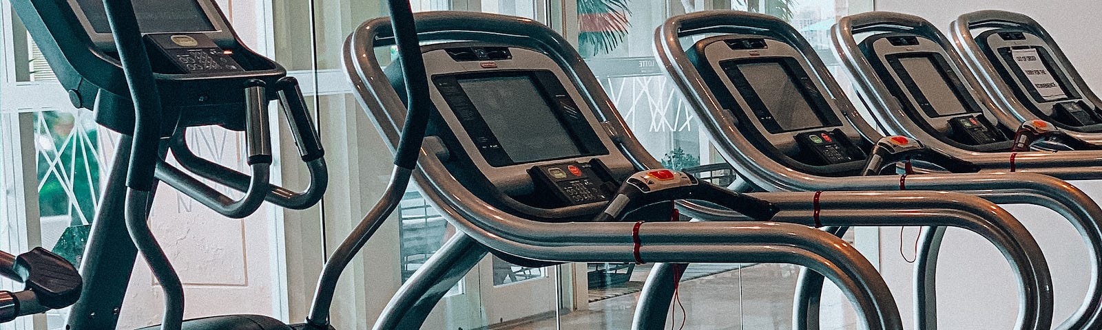 Several exercise machines, including a stairmaster, in a row