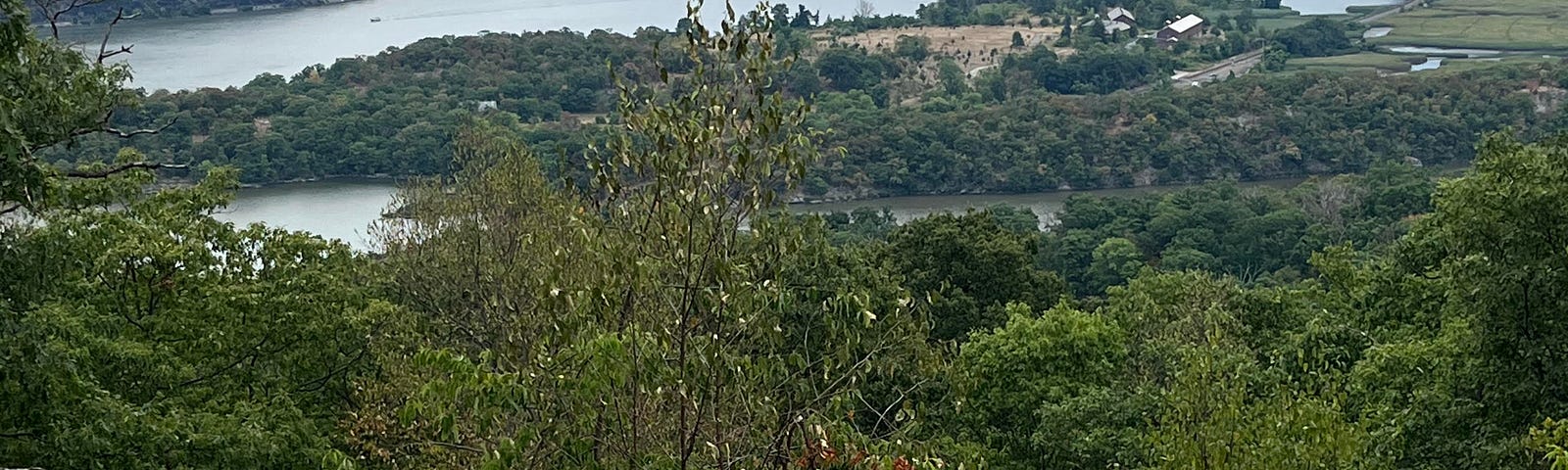 View of a lake in a valley, with lush green landscape, from a rocky out-cropping on which the photographer stands.