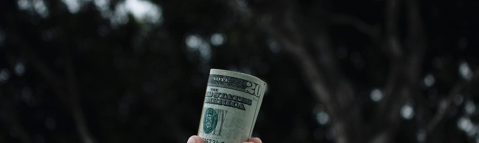 Photo of a hand holding a roll of money.