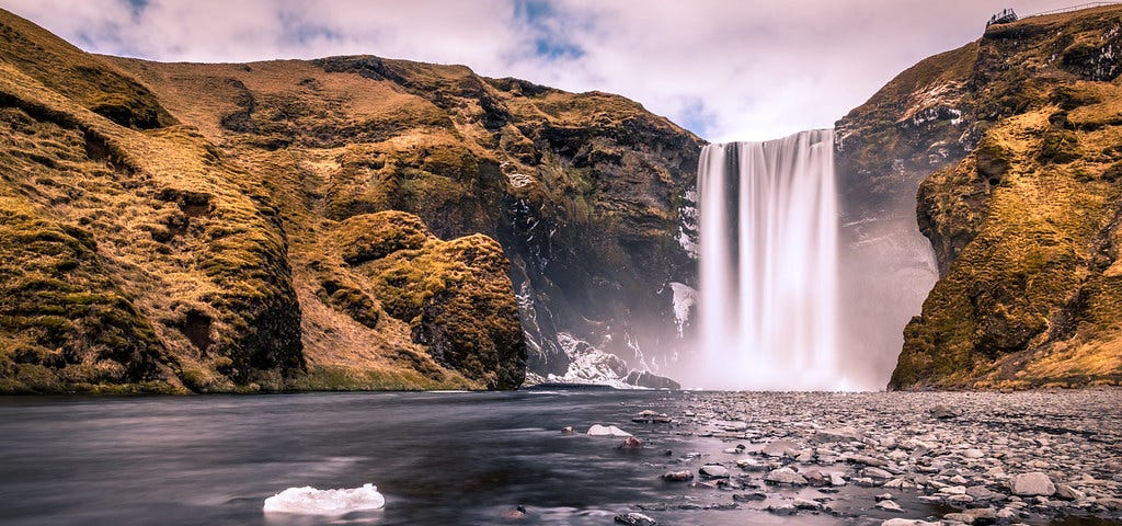 A waterfall falling into a beautiful lake.