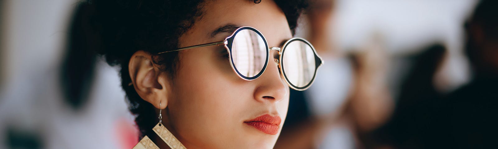 Woman facing sideaways with a pair of gold and black sunglasses.