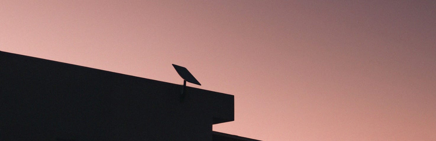 IMAGE: The silhouette of a Starlink antenna in a roof on a purple sky