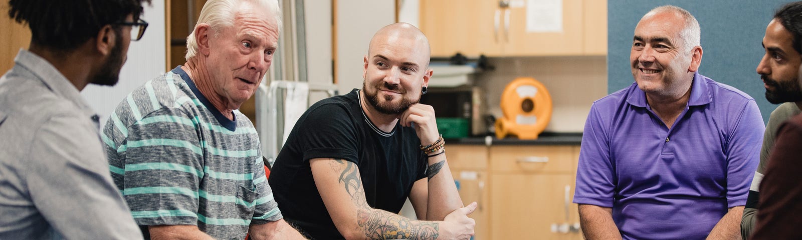 Group of men sat talking together in a mental health support group.