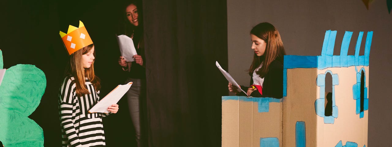 Drama teacher watching her students rehearse on stage.