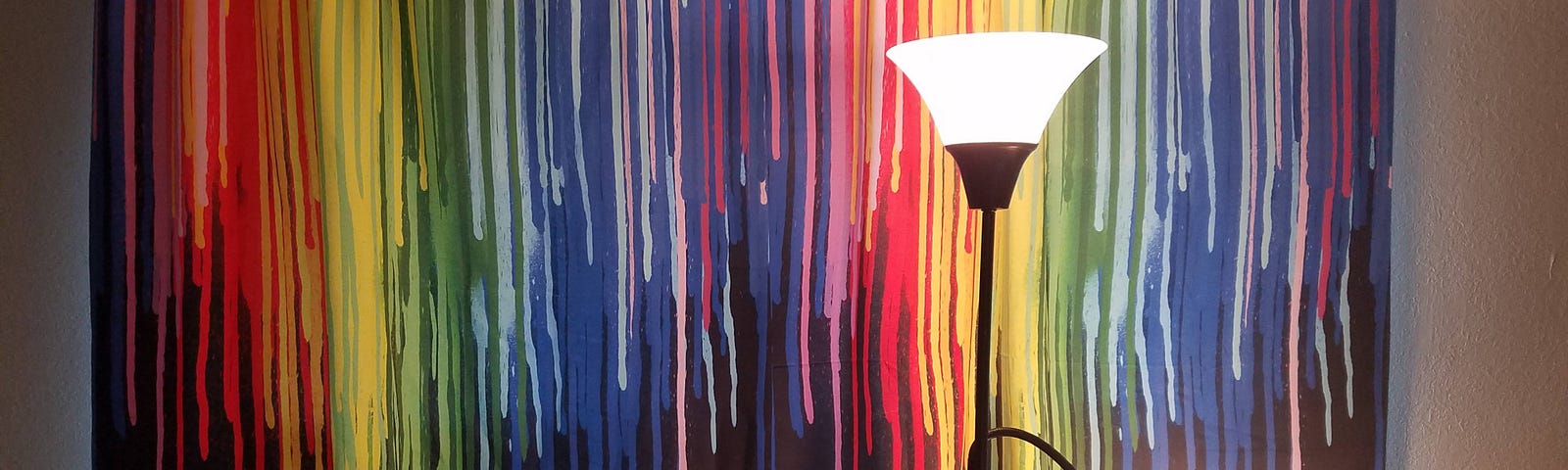 Black Curtains with rainbow colored paint effect. In front of the curtains, a light and an easy chair