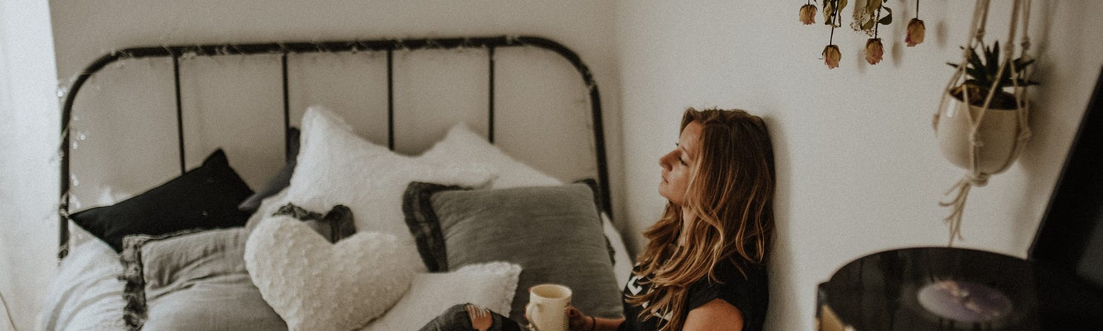 A woman sitting on a bed drinking coffee.