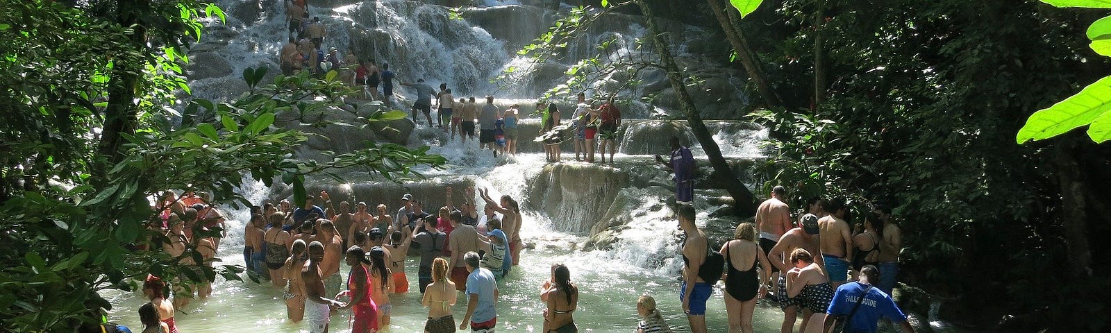 A picture of Dunn’s River Falls, many people are walking up the falls dressed in swim suits or shorts and t-shirts