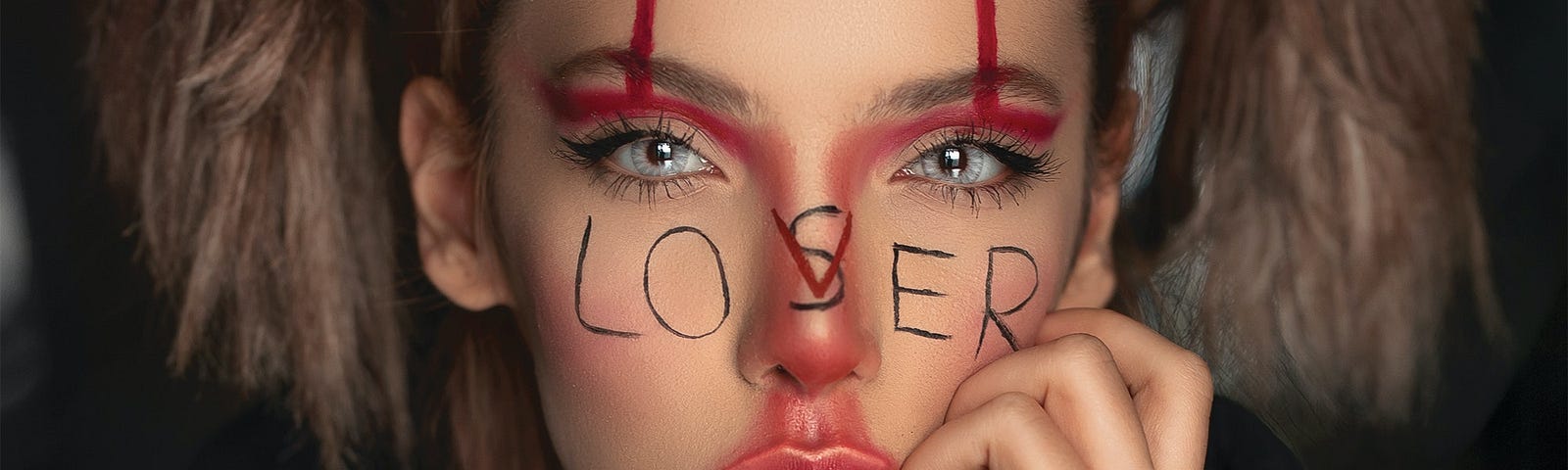 Woman with pigtails, clown-like make-up and Loser written over her face.