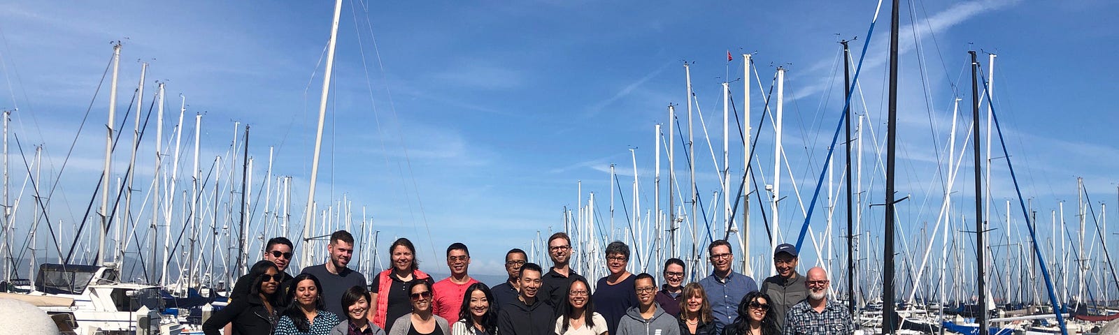 A picture of the Digital Services Team members smiling in the sun in front of some boats at the waterfront in San Francisco